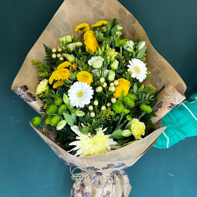 Golden Glow - A vibrant bouquet featuring yellow roses, white gerberas, and green chrysanthemums. Wrapped in rustic brown paper, it’s perfect for sending warm and cheerful wishes.