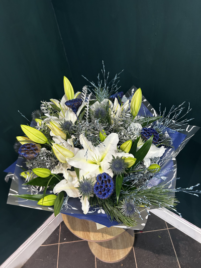 The North Star - The North Star features snowy white oriental lily and beautiful blue thistle all surrounded by festive silver and blue foliage and with added sparkle with blue glittered lotus seed heads. 

Part of our alternative Christmas design range created live on TikTok